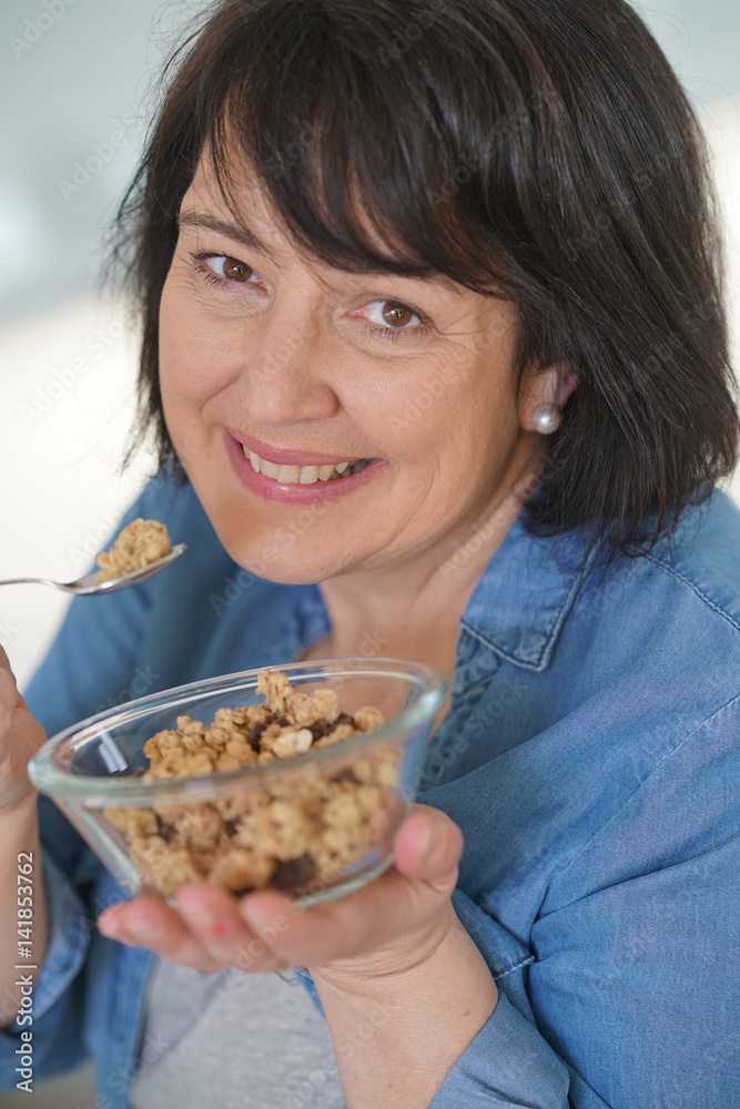 Dark-haired woman in kitchen eating cereals Dark-haired woman in kitchen eating cereals