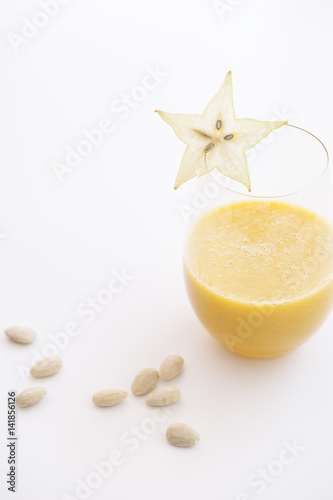 Fresh yellow fruit juice, smoothie, with almonds, oranges, pineapple, star fruit and bananas photo