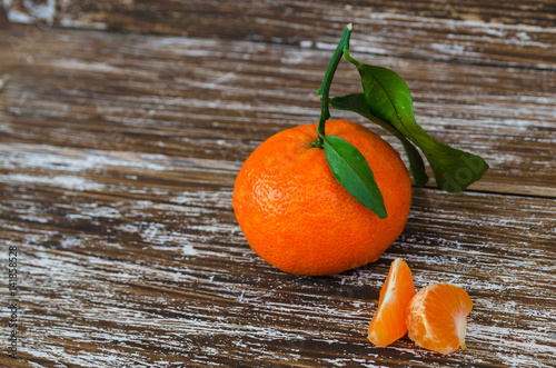 Close up of whole mandarin with leaves and mandarin slice on wood table. Organic tangerine fruit background with copy space.