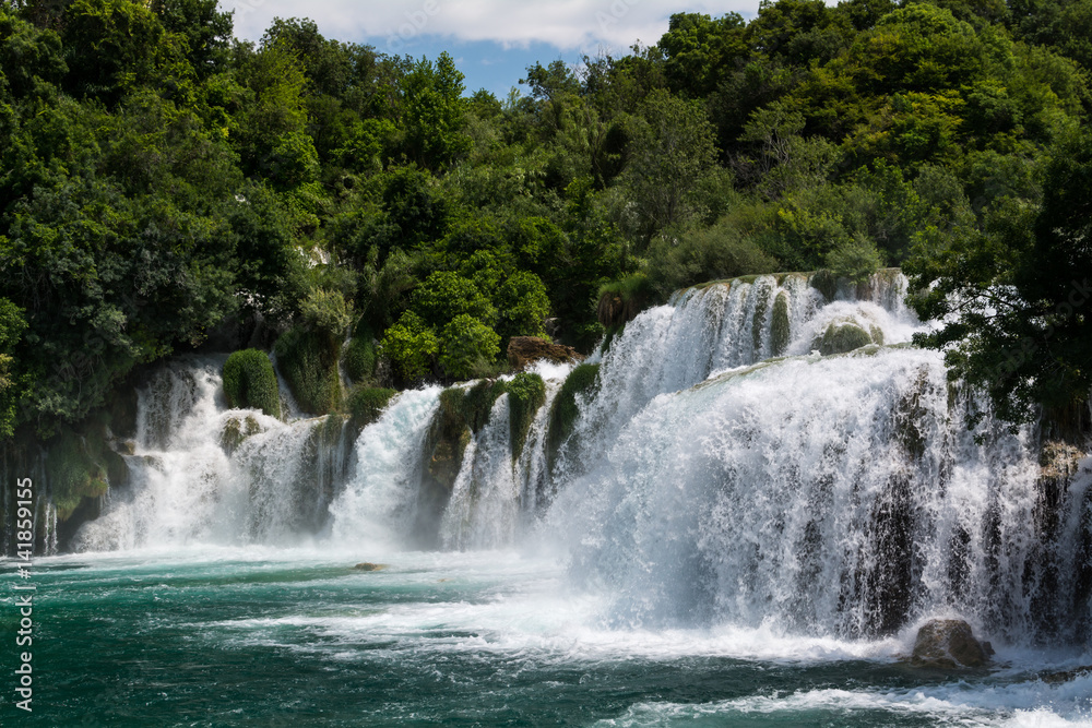 Fototapeta premium Spienione kaskady wodospadu spadają kaskadami wodospadu Skradinski Buk w słoneczny dzień. Park Narodowy Krka, Chorwacja.