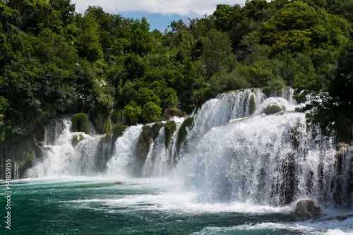 Foamy waterfall rapids falling down by cascades of waterfall Skradinski Buk on a sunny day. Krka National Park, Croatia.