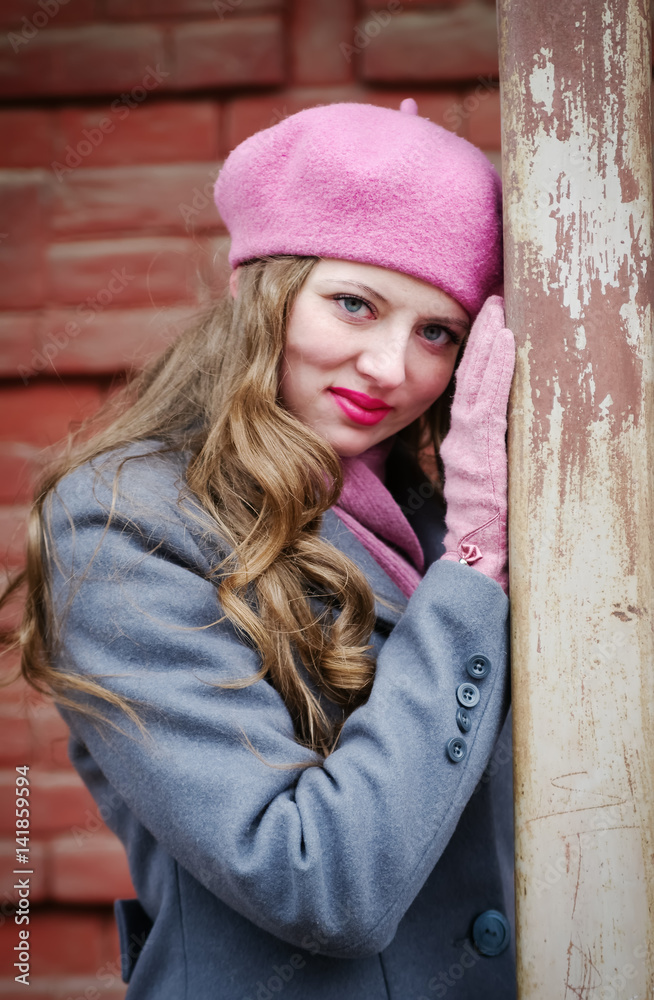 Fototapeta premium Portrait of a girl in a pink beret and a gray-blue coat / The picture was taken in Russia, in the city of Orenburg, in a courtyard on Kobozev street
