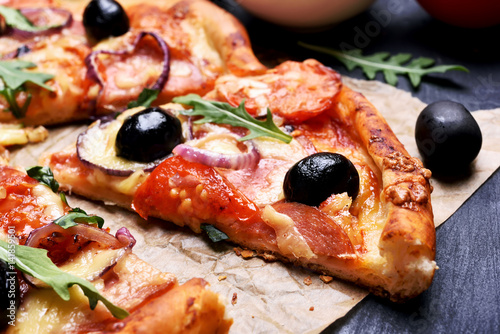 Slice of pizza with tomato, salami and olives