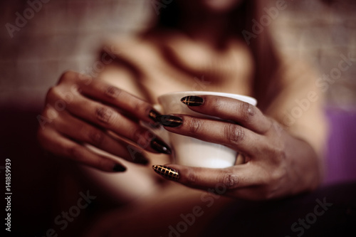 Hands of a woman holding a coffee mug.