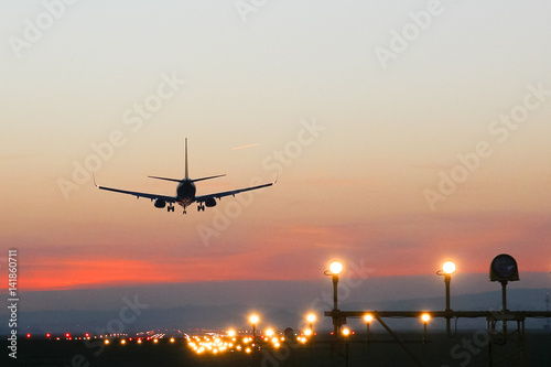 Plane lands at an airfield on the background of sunset
