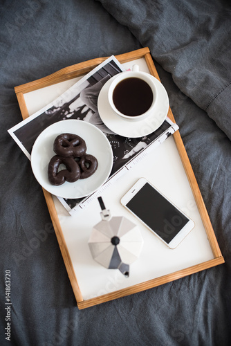 Coffee and breakfast in bed, smartphone and magazine