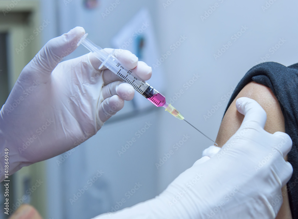 Close-up hands,nurses are vaccinations to patients using the syringe.Doctor vaccinating women in hospital.Are treated by the use of sterile injectable upper arm. injection Close-up hands,nurses are vaccinations to patients using the syringe.Doctor vaccinating women in hospital.Are treated by the use of sterile injectable upper arm. injection