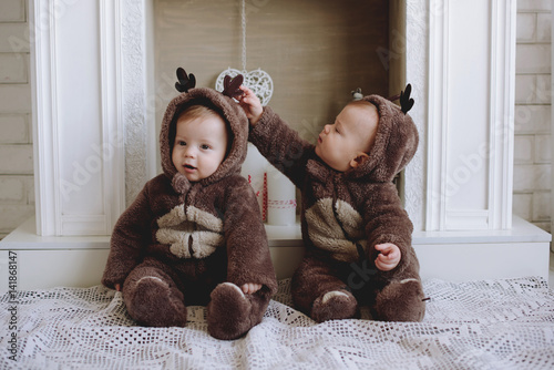 Two twin babies boys. They are setting together in a deer costumes.Four week old fraternal, twin, baby boys wearing deer hats.