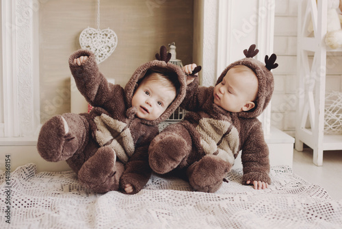 Two twin babies boys. They are setting together in a deer costumes.Four week old fraternal, twin, baby boys wearing deer hats.