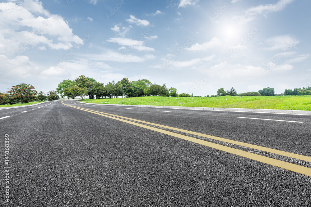 Asphalt road and green trees in the blue sky Asphalt road and green trees in the blue sky