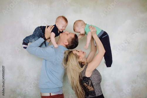 Father and mother playing with two little sons.Two little kid boys, siblings twins and parents having fun. Happy father, mother and two children playing together.