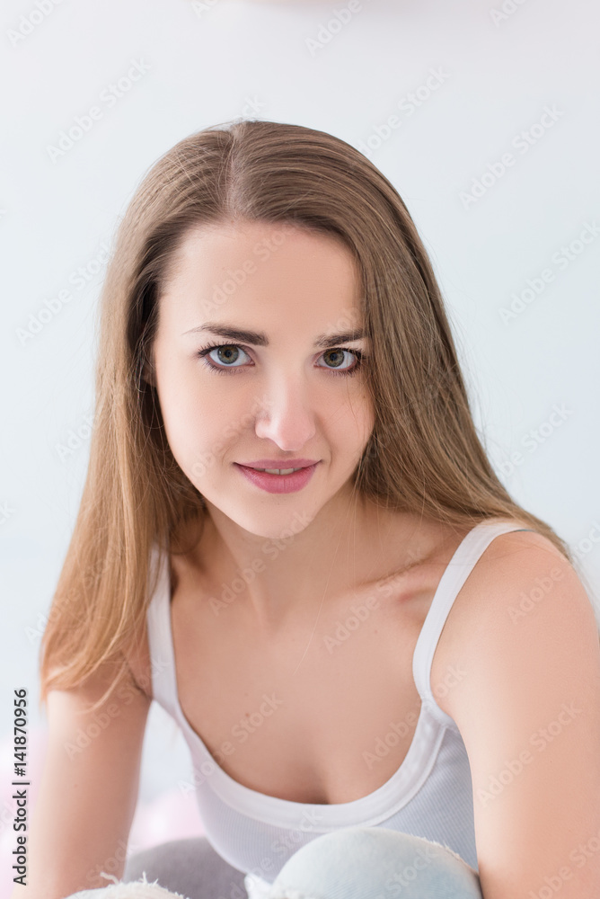 Beautiful young model with long brown hair looking at camera. Natural beauty portrait of woman on white Beautiful young model with long brown hair looking at camera. Natural beauty portrait of woman on white