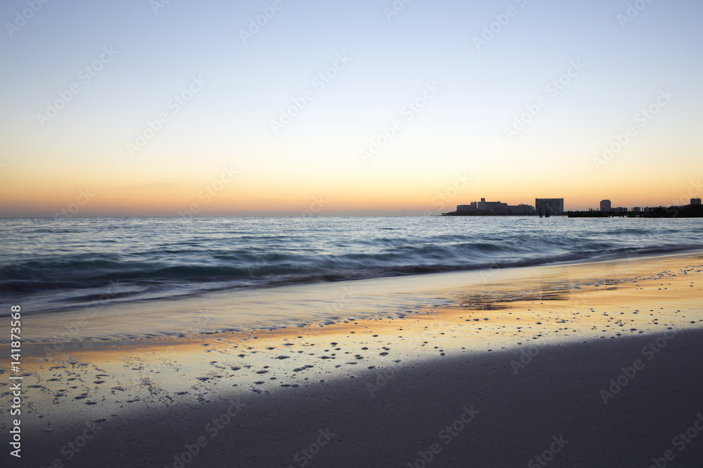 Sunrise on the beach. The caribbean sea is about to wake up. Sun coming up behind the horizon. Long exposure image.
