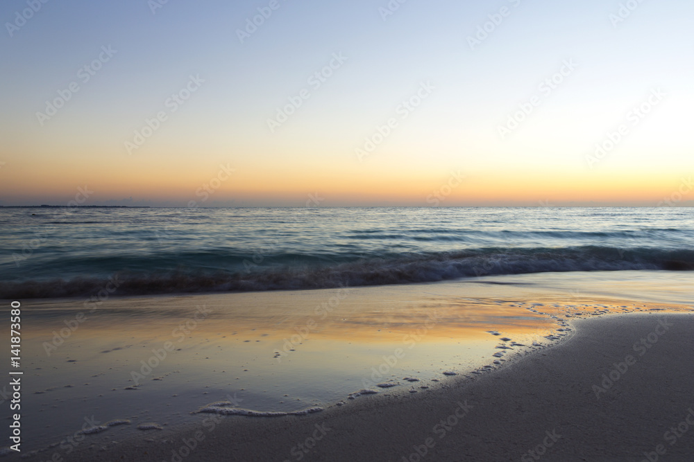 Sunrise on the beach. The caribbean sea is about to wake up. Sun coming up behind the horizon. Long exposure image. Focus point on the right side of the image.