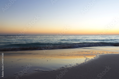 Sunrise on the beach. The caribbean sea is about to wake up. Sun coming up behind the horizon. Long exposure image. Focus point on the right side of the image.