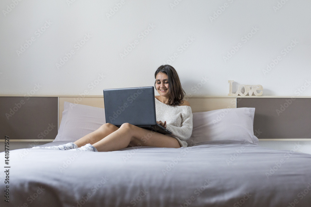 beautiful young woman lying on bed, using laptop. Lifestyle.