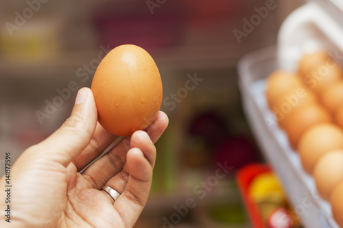 A man picking an egg from a fridge. 