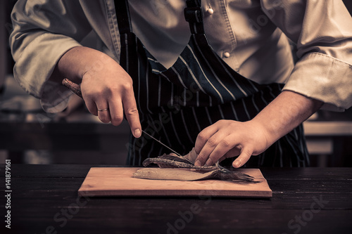 Chef cutting the fish on a board