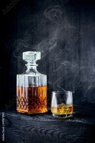 Glass of whiskey and carafe on a black wooden table