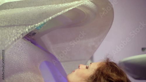 Young pretty woman taking treatments in the spa capsule siow mo photo