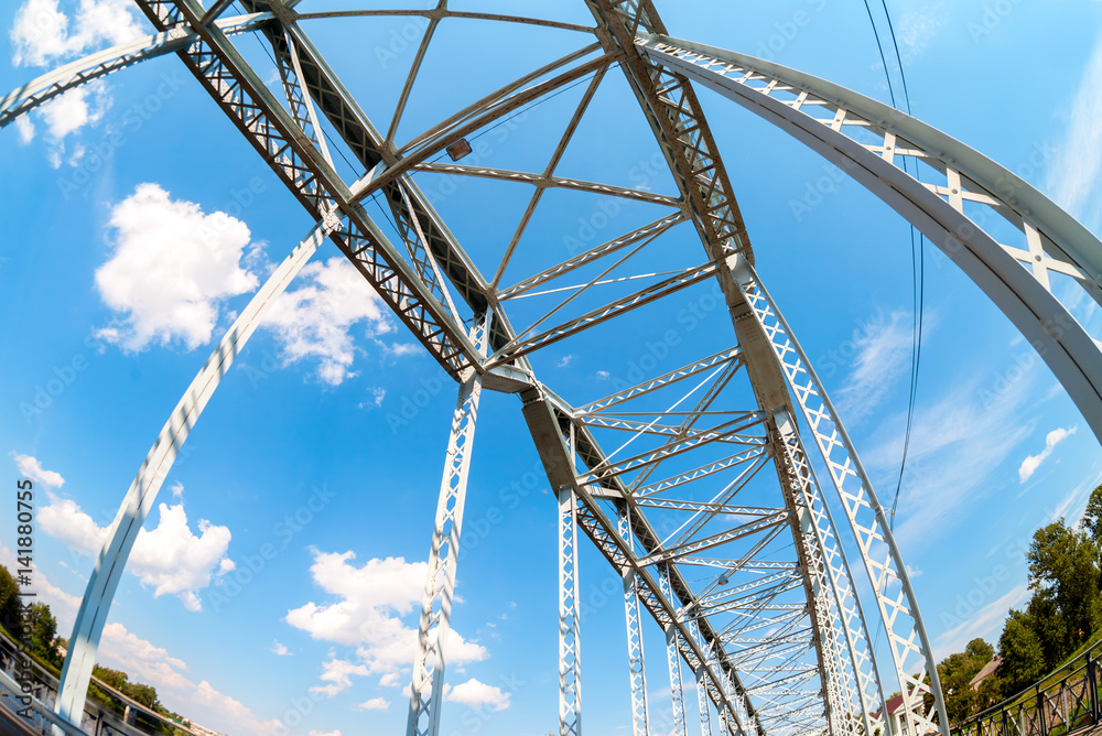 First in Russia steel arch bridge on river Msta. Historic iron bridge against blue sky