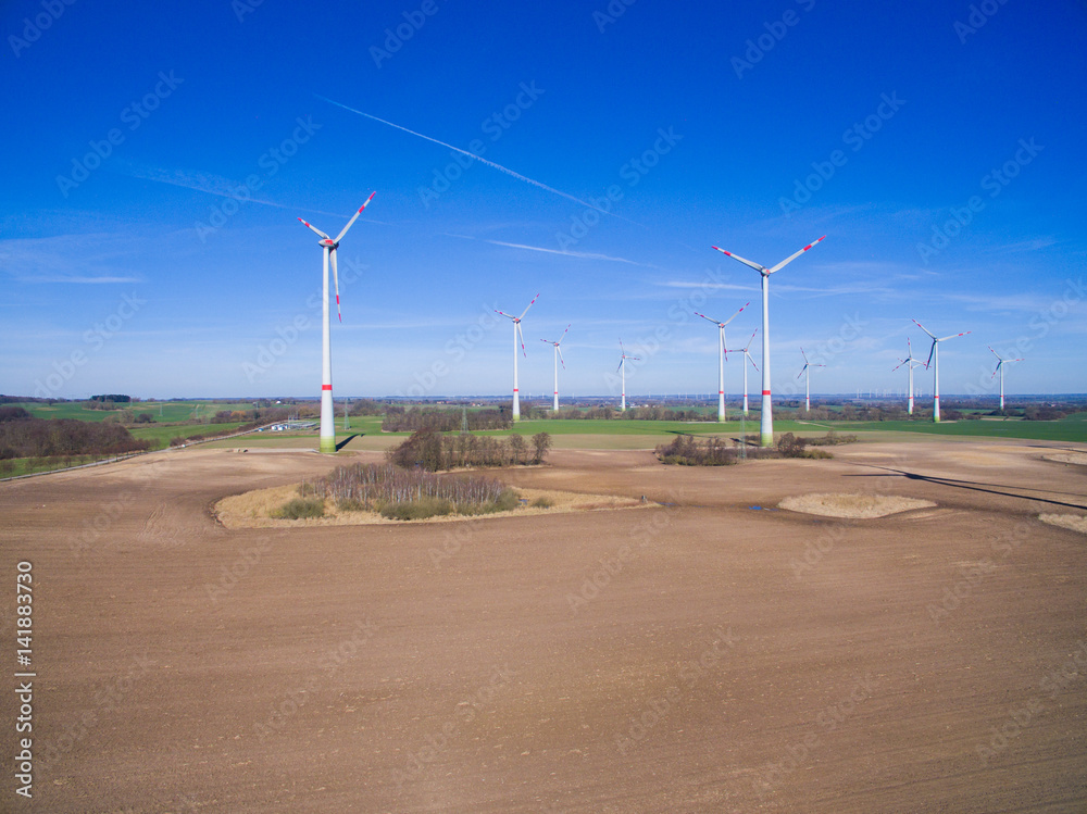 
Wind turbines farm in rural area with agricultural fields under blue sky - aerial view germany