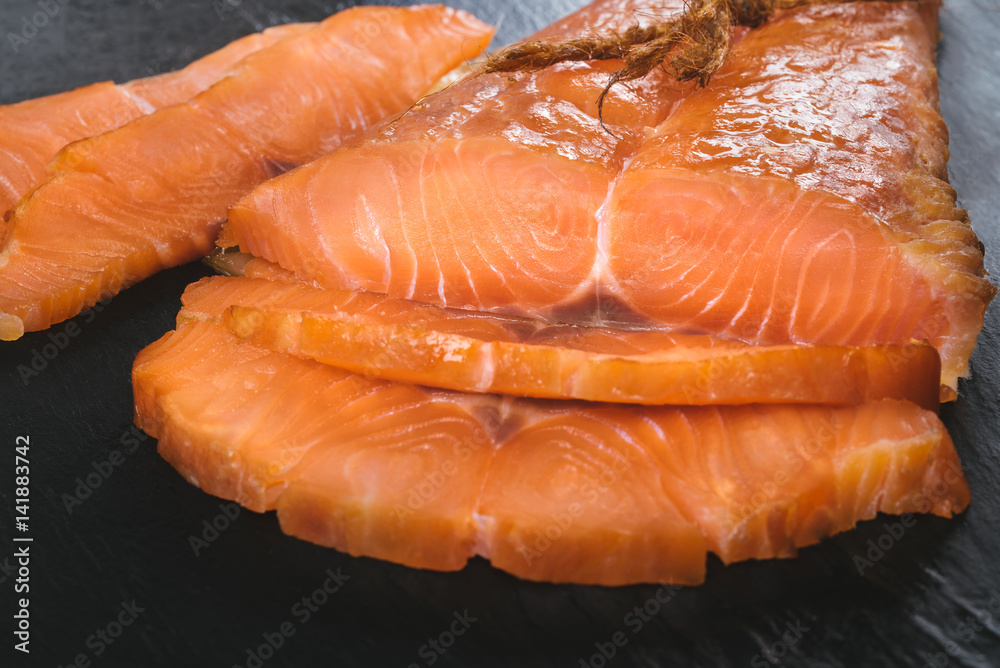 Smoked salmon fish on a slate board. Cutted slices of smoked salmon. Tasty smoked fillet of red fish Smoked salmon fish on a slate board. Cutted slices of smoked salmon. Tasty smoked fillet of red fish