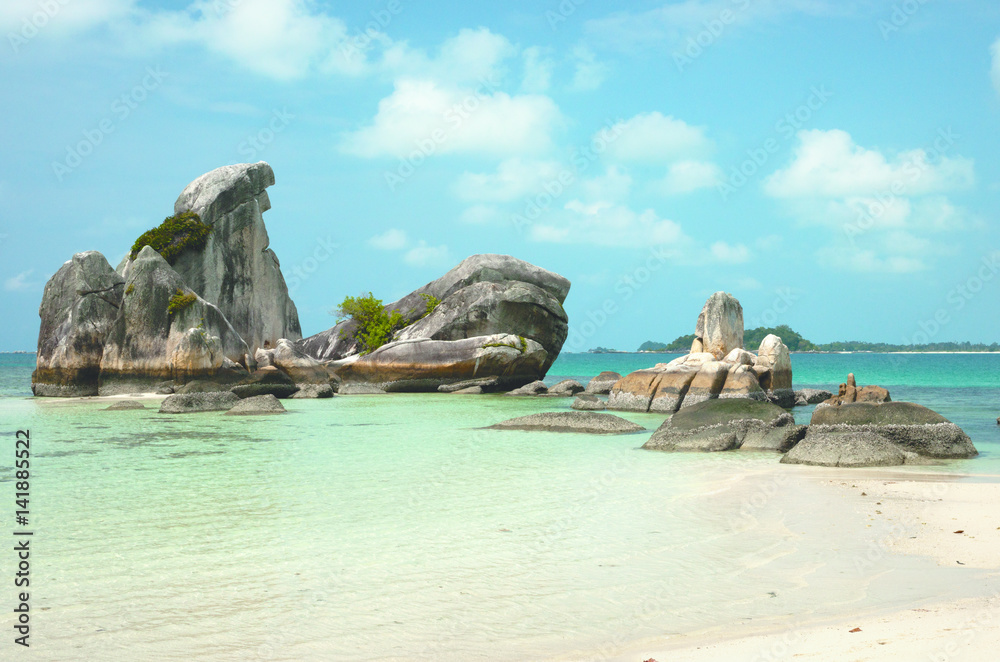 Natural rock formation in the sea and on a white sand beach in Belitung Island in the afternoon, Indonesia.