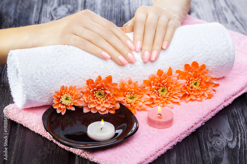 beautiful pink manicure with chrysanthemum and towel on the black wooden table. spa
