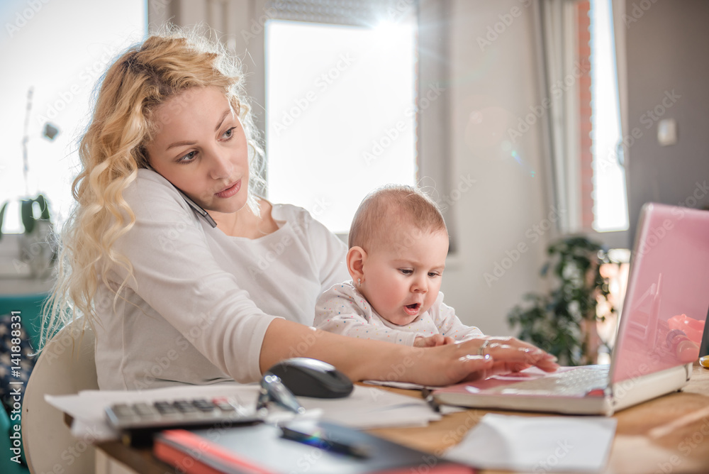 Mother talking on smart phone at home office Mother talking on smart phone at home office