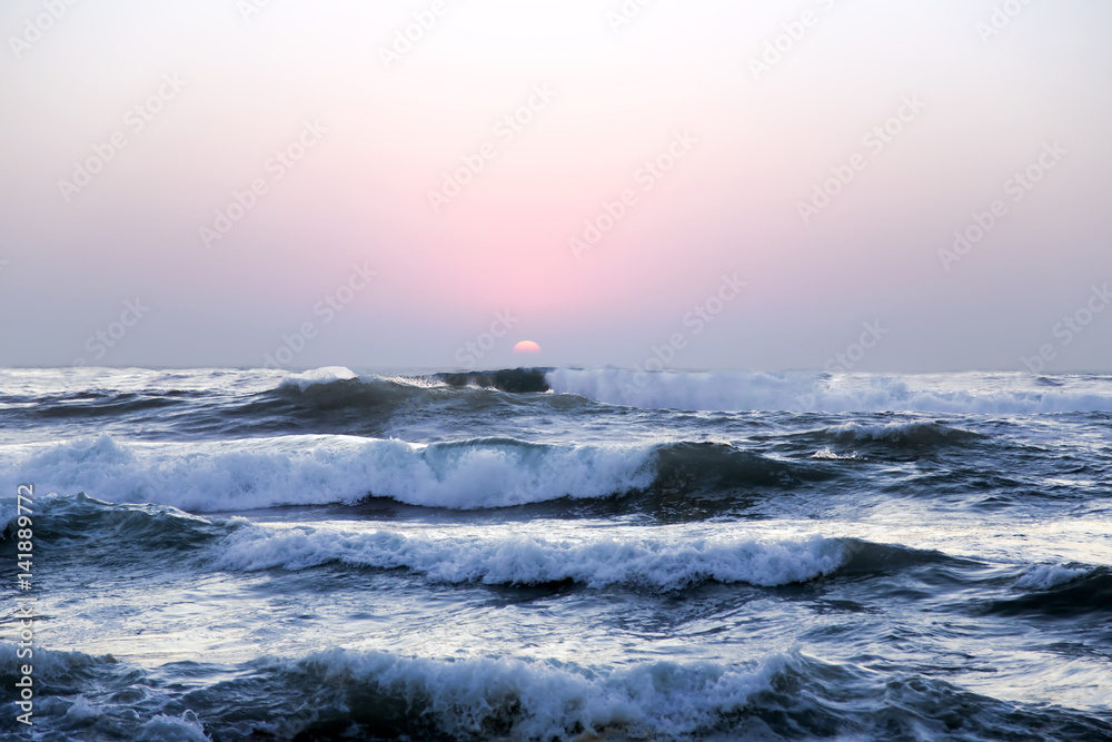 Obraz premium Large waves of the Atlantic Ocean on a sunset background in Lisbon, Portugal