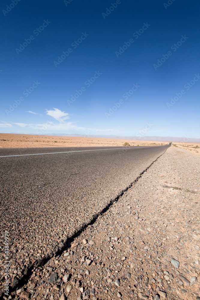 Naklejka premium route droite au milieu d'un désert de sable 