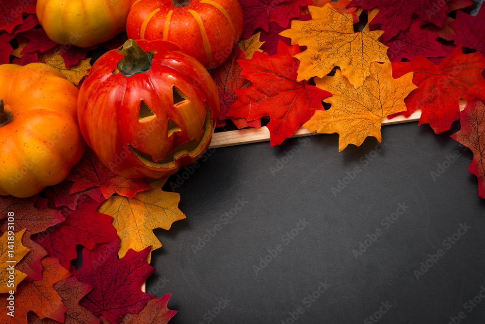 Halloween still life with jack o'lantern, pumpkins, fallen orange leaves and copyspace on a blackboard for your Halloween holiday text Halloween still life with jack o'lantern, pumpkins, fallen orange leaves and copyspace on a blackboard for your Halloween holiday text