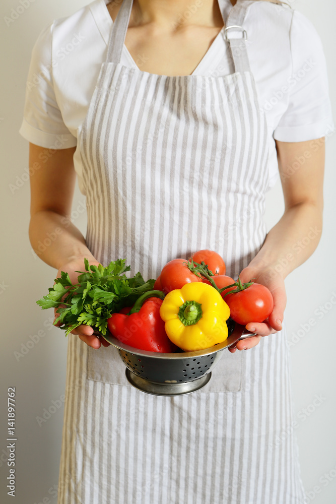 Cook holding a colander with vegetables, without face Cook holding a colander with vegetables, without face