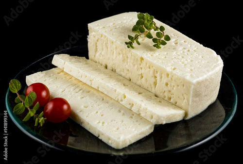 Slices of traditional sfella cheese of Peloponnese, Greece, on plate with little tomatoes and oregano photo