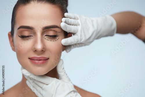 Closeup Of Beautician Hands Touching Young Female Patient Face photo