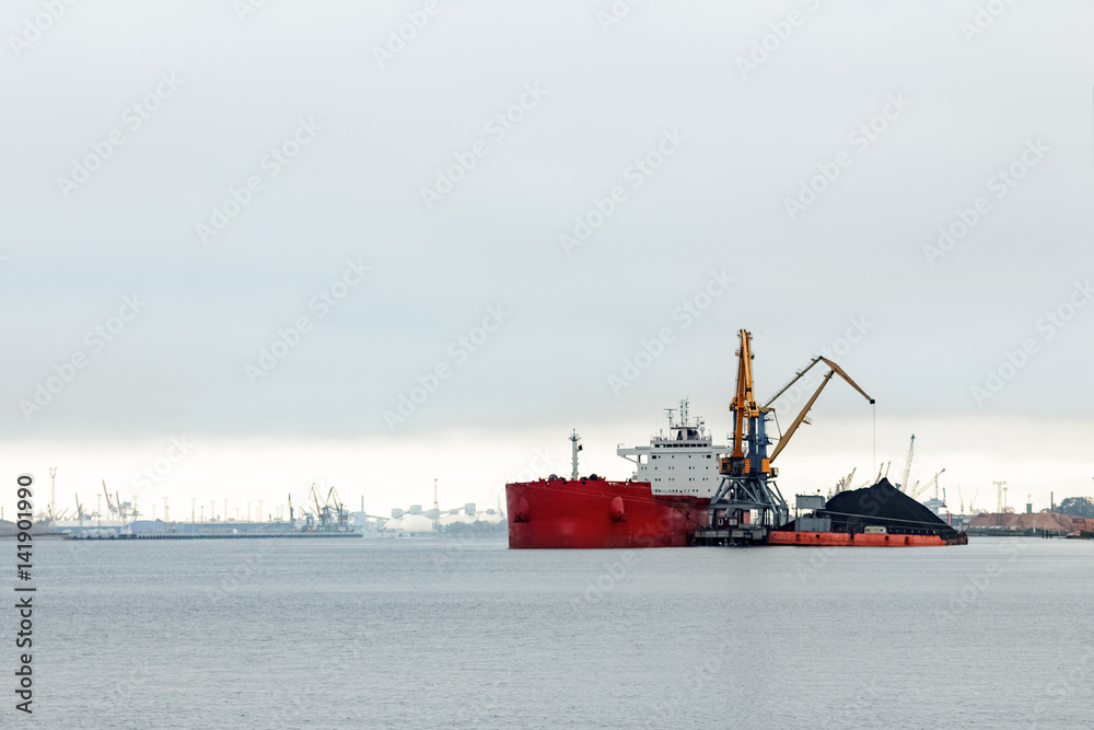 Large red cargo ship loading with a coal in the port Large red cargo ship loading with a coal in the port