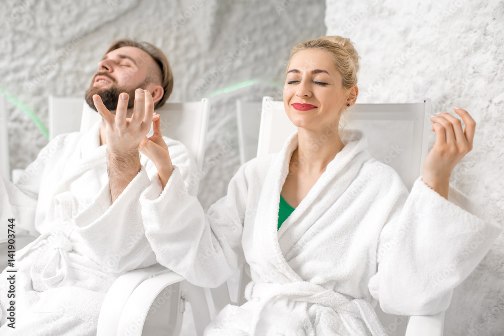 Young couple in bathrobes meditating in the salt room Young couple in bathrobes meditating in the salt room