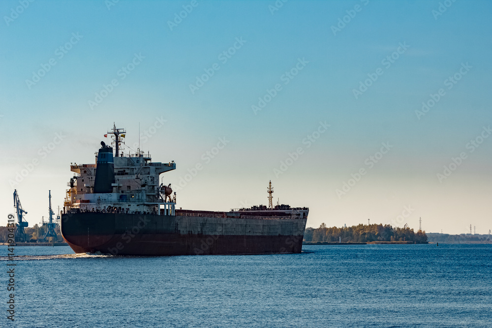 Black cargo ship entering Riga, Europe