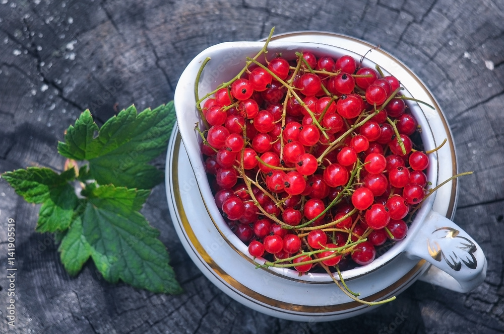 ripe red currant in an old ceramic vase on a wooden background ripe red currant in an old ceramic vase on a wooden background
