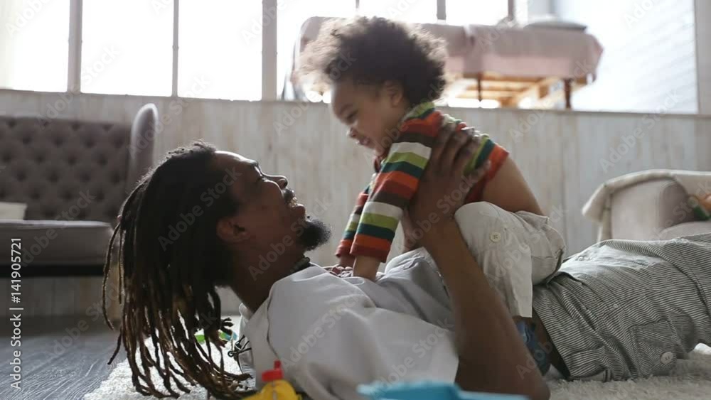 Cheerful father and toddler son having fun at home