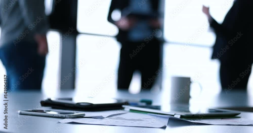 Devices on table with business people in background in modern office building Devices on table with business people in background in modern office building