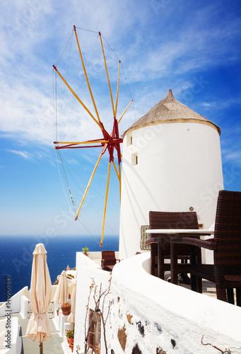 windmill of Oia at sunny day with blue sea and sky close up, Santorini, toned
