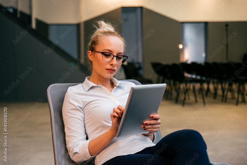 Business woman sitting in her office using a tablet computer, preparing presentation Business woman sitting in her office using a tablet computer, preparing presentation