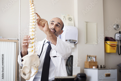 Doctor pointing on spinal disk while working in hospital photo