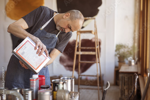 Artist pouring paint from container at workshop photo