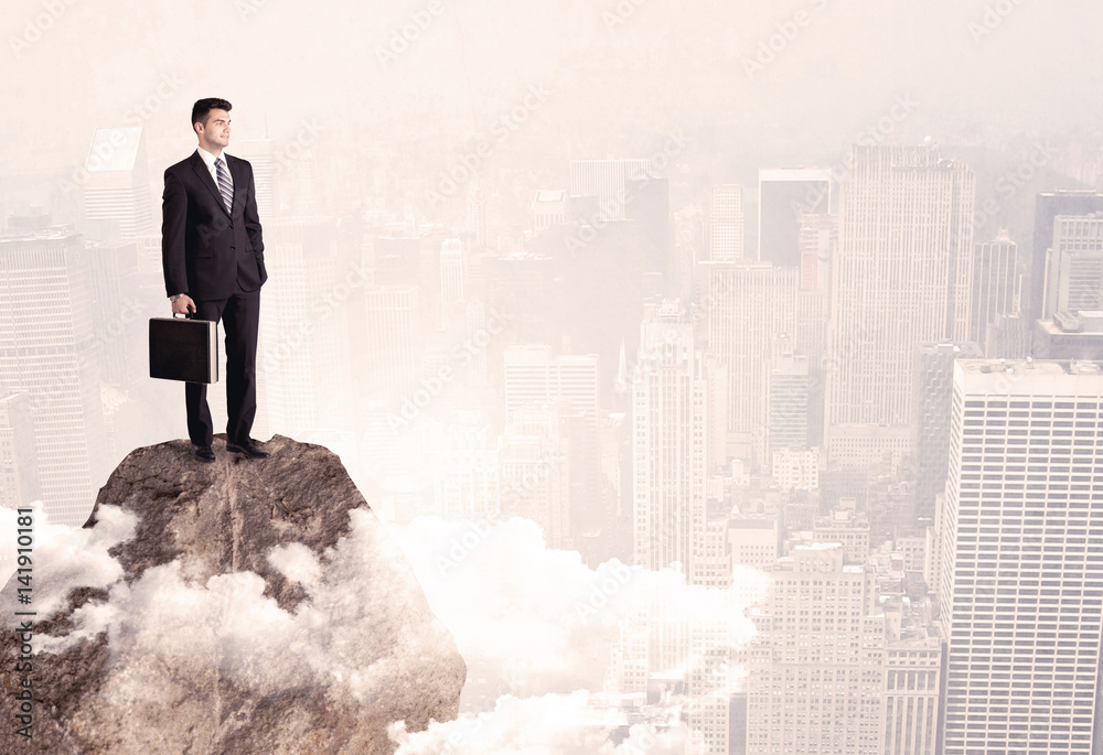 Happy businessman standing on stone top Happy businessman standing on stone top
