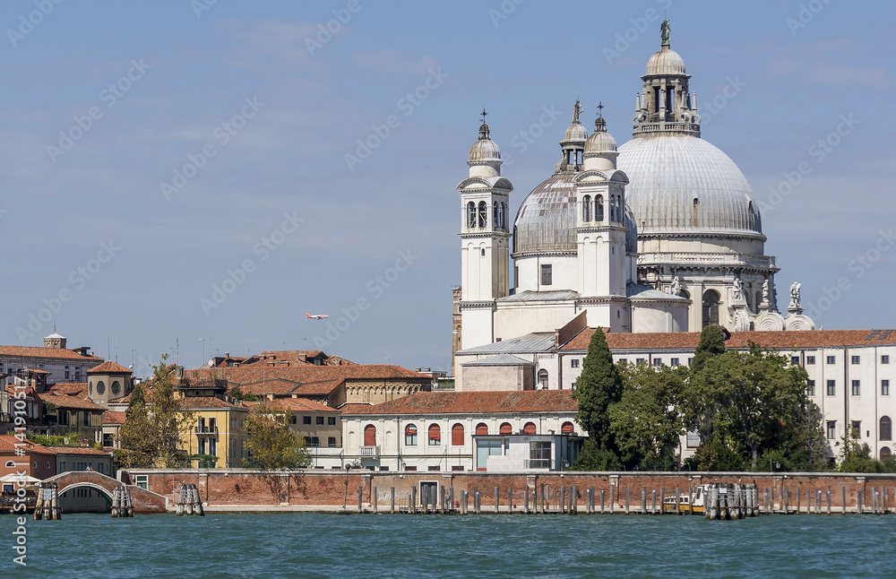 Beautiful view of the Basilica of Santa Maria della Salute from the lagoon with an airplane in the background, Venice, Italy