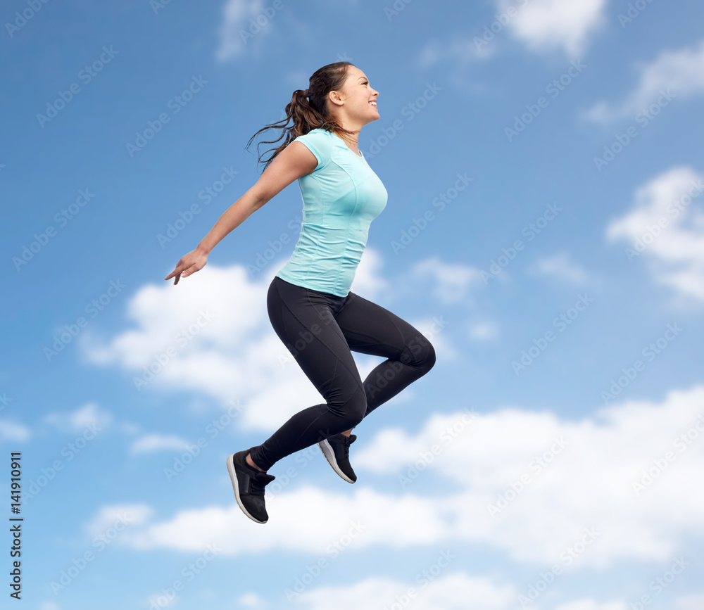 happy smiling sporty young woman jumping in sky