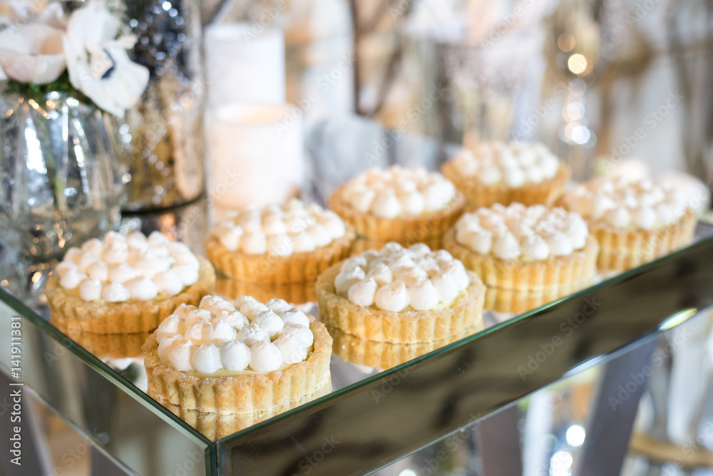Cupcakes with white cream on the table decorated with white flowers and candles